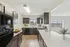 Modern kitchen with sleek dark cabinets, stainless steel appliances, and a bright open concept leading to a scenic living area.