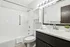 Modern bathroom featuring elegant white subway tiles, sleek fixtures, and a large mirror for a bright, luxurious feel.