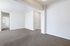 Inviting apartment interior featuring an open living area with fresh white walls and plush carpet, leading to a sunlit hallway.