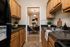 Charming kitchen with natural wood cabinets, modern black appliances, and a view into a cozy dining area with stylish blue chairs.
