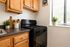 Charming kitchen with sleek black stove, warm wooden cabinets, and abundant natural light from large window.