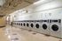 Bright and spacious laundry facility showcasing modern washing machines lined against a well-lit wall.