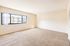 Bright and spacious room with large window offering a charming view, featuring soft carpet and neutral walls perfect for personal customization.