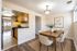 Elegant dining area with a wooden table for six, open to a modern kitchen with warm cabinetry and sleek appliances, perfect for entertaining.