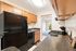 Bright and inviting kitchen with sleek black appliances, warm wooden cabinets, and a view into a sunlit living area.