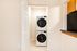 Modern laundry area featuring a sleek stacked washer and dryer set in a compact, well-lit space.