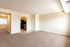 Bright and spacious living room with plush carpet and open access to a modern kitchen featuring sleek black appliances.