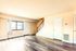 Bright and inviting living area featuring modern laminate flooring, sunlit windows, and elegant staircase in a charming apartment.
