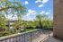 Charming balcony view with lush greenery and clear blue skies, perfect for relaxation in a serene suburban setting.
