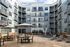 Modern apartment complex courtyard with stylish outdoor seating, unique sculpture, and contemporary architecture.