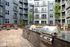 Modern apartment courtyard with sleek barbecue grills, cozy seating, and lush greenery for outdoor relaxation.