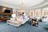 Inviting open-concept living room featuring elegant gray sofas, modern stone fireplace, stylish lighting fixture, and abundant natural light.