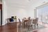Bright dining area with elegant wooden table, cozy chairs, and a stylish rug beside a modern workspace in an apartment with natural light.