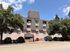 Charming apartment building with classic brick exterior, surrounded by lush trees under a clear blue sky.