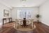 Bright and inviting dining area featuring a round wooden table, elegant chairs, and a large window with natural light.