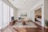 Inviting living room with ample natural light, cozy beige sofa, elegant wooden coffee table, striped area rug, and sliding door leading to a stylish bedroom.