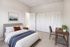 Inviting bedroom featuring a cozy bed with stylish accents, ample closet space, and a compact workspace, perfect for comfort and functionality.