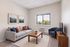 Inviting living room with a cozy gray sofa, vibrant throw pillows, modern artwork, and a large window offering scenic views, perfect for relaxation.