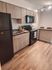 Chic modern kitchen with stylish wooden cabinets and sleek black appliances, featuring a cozy breakfast bar and elegant lighting.