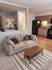 Modern apartment interior featuring a cozy beige sofa with colorful pillows, elegant wooden coffee table, and sleek kitchen with stylish cabinetry and lighting.
