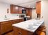 Modern kitchen with elegant wood cabinetry, sleek white countertops, and a cozy breakfast bar set with dishes and glasses.