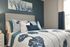 Elegant bedroom with a plush bed adorned with blue and white accent pillows and floral bedding, complemented by modern artwork.