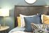 Inviting bedroom setup featuring a stylish wooden headboard, plush pillows, and a modern bedside lamp.