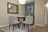 Modern dining area with a round table, four stylish chairs, and a large mirror on the wall.