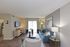 Inviting living room with stylish decor, featuring a blue sofa, modern art, and ample natural light.