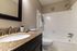 Chic bathroom with granite countertop, modern fixtures, and bathtub surrounded by sleek tiles.