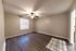 Spacious bedroom with elegant wooden flooring and ceiling fan, featuring a large window for ample natural light.