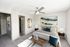 Modern bedroom with stylish decor, white and blue bedding, abstract wall art, and natural light.