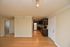 Modern apartment interior showcasing an open kitchen with sleek cabinets and a bright living space with hardwood floors.