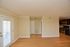 Sunlit open area with wooden flooring and a modern kitchen featuring stainless steel appliances.