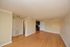 Bright, open-concept living room with glossy hardwood floors and modern lighting, adjacent to a sleek kitchen.