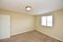 Inviting bedroom with plush carpet, beige walls, and ample natural light from a large window.