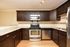 Contemporary kitchen with dark wood cabinets, granite countertops, and stainless steel appliances.