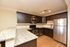 Elegant kitchen with modern appliances, dark wood cabinets, granite countertops, and track lighting.