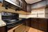 Modern kitchen featuring dark wood cabinets, stainless steel appliances, and intricate backsplash tiles.