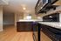 Modern kitchen with granite countertops, stainless steel appliances, and open living area with hardwood floors.