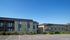 Charming two-story apartment buildings with balconies and landscaped surroundings under a clear blue sky.