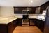 Modern kitchen with dark wood cabinets, stainless steel appliances, and granite countertops.