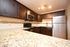 Modern kitchen with dark cabinets, granite countertops, stainless steel appliances, and elegant lighting.