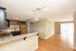 Bright open kitchen with granite countertops and wooden floors extending into a spacious living area.