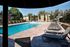 Inviting pool area with modern sun loungers and lush greenery in a tranquil apartment complex setting.