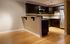 Sleek kitchen with modern steel appliances, dark wood cabinets, and an adjacent open-concept living area with light hardwood floors.