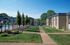 Beautiful apartment complex with lush landscaping, a pool, and sunny walkways.