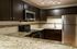 Modern kitchen with granite countertops, stainless steel appliances, and dark wood cabinetry.