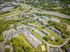Aerial view of a spacious apartment complex surrounded by lush greenery and connected by well-maintained roads.