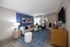 Stylish living room with modern decor, featuring a cozy cream sofa, blue accent wall, and elegant furnishings.